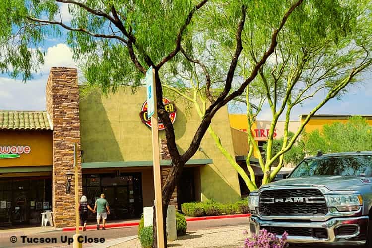 truck in a parking lot with desert trees and a couple entering a restaurant
