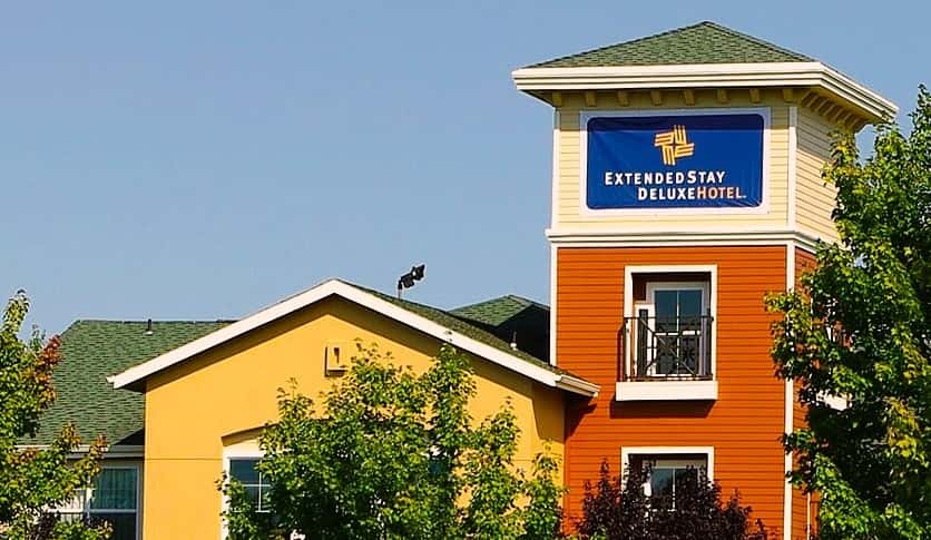 front view of an extended stay hotel framed by trees