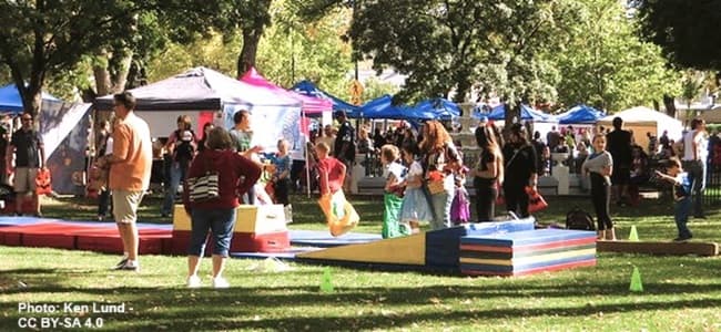variety of tents and booths with people attending a farmer's market variety of tents and booths with people attending a farmer's market