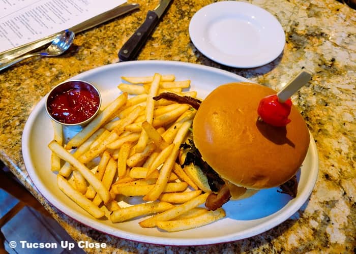 a plate on a counter with a hamburger, french fries, and ketchup
