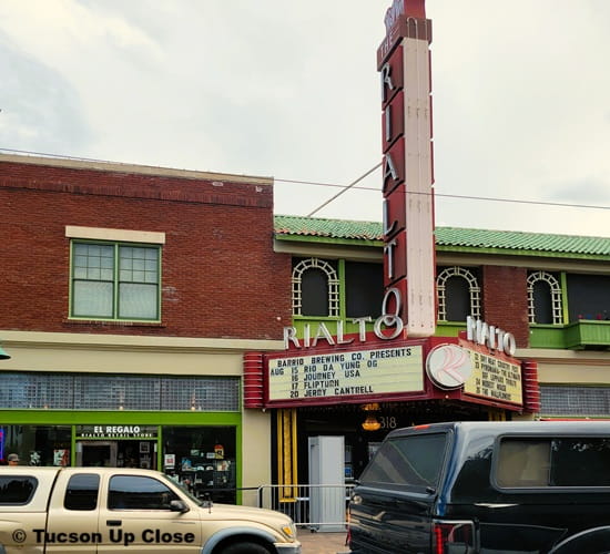 cars on a downtown Tucson street ride by the Rialto marquee.