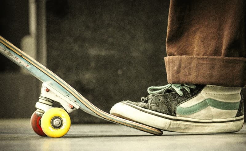 boy with athletic shoes steps on skateboard end