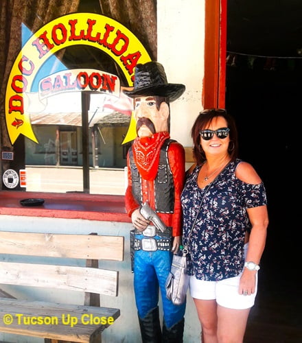 Woman standing next to large cowboy statue in front a local Tombstone Arizona establishment