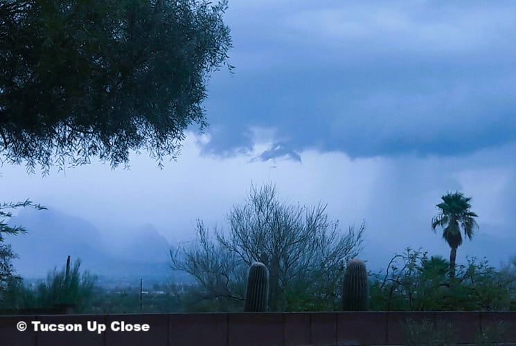looking down a hillside into Tucson while a rainstorm is in the works