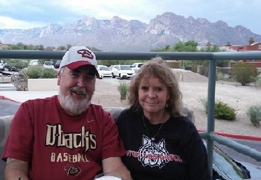 man and woman seated at a table with a view of mountains behind them