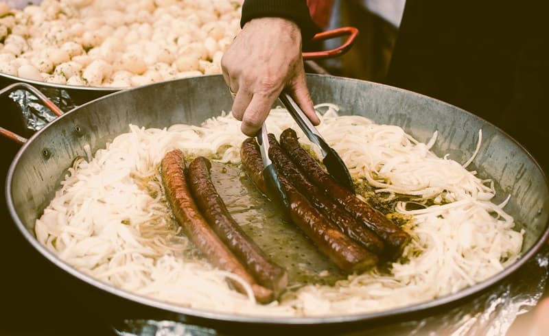 a wok with noodles and chinese chorizo sausage cooking