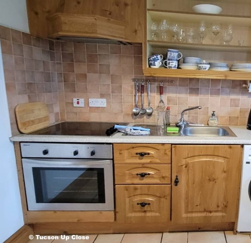 part of a kitchen with stove, sink and shelves