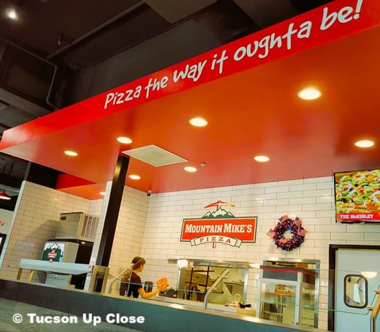 person standing behind counter of a pizza restaurant