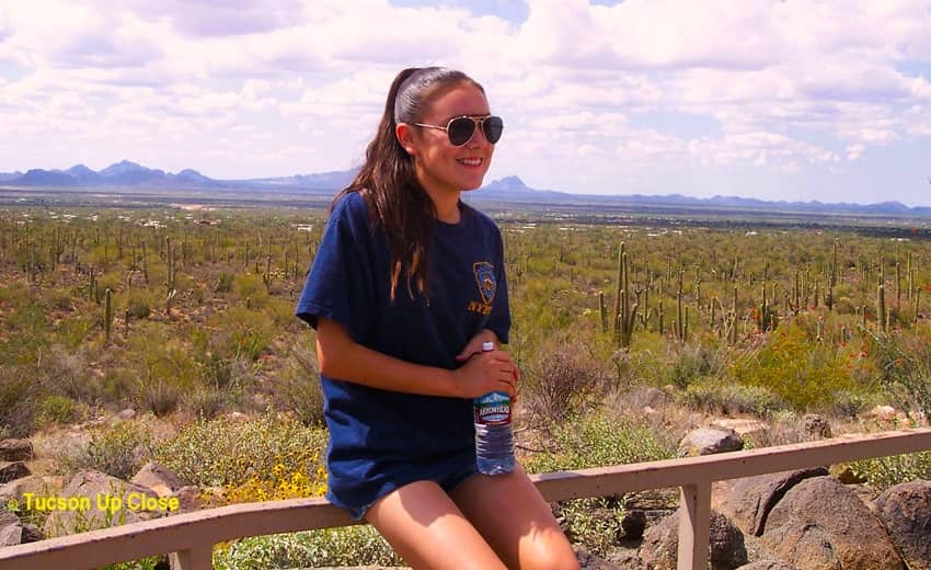 Girl leaning a a fence in a desert setting