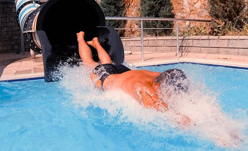 boy sliding out from a waterslide into a swimming pool