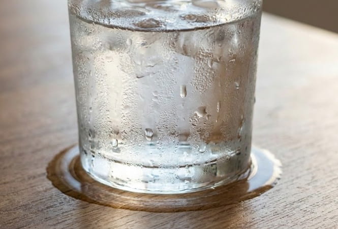 glass of water on a table that is sweating from condensation 